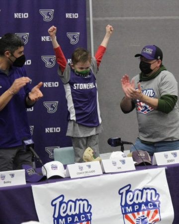 Ian puts two fists high in the air to celebrate his signing