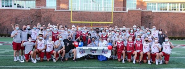Mens lacrosse team poses with Braxton in a big team photo on the field