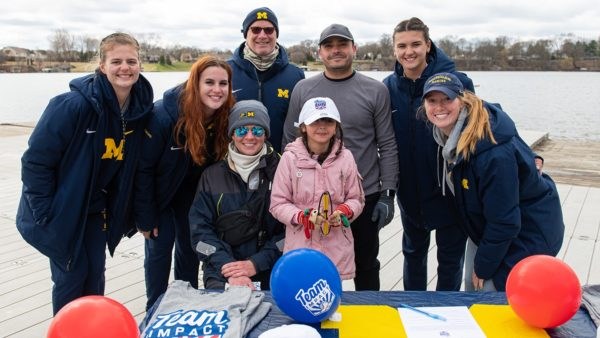 Michigan Wolverine team poses with a smiling Charlie for a photo