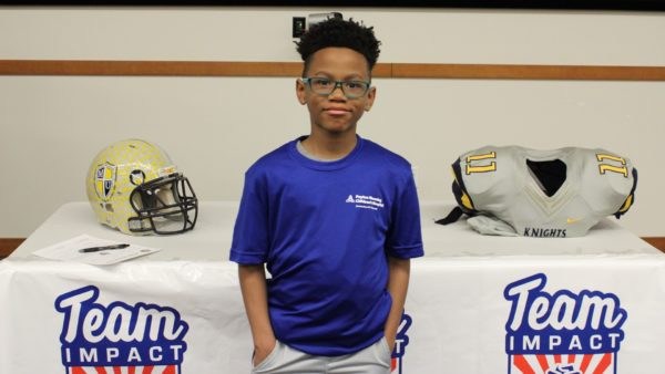 Trace smiles for the camera with his football helmet and shoulder pads behind him